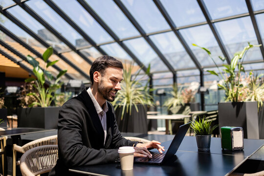 Smiling man working on laptop in modern cafe
