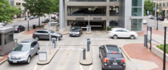 Fototapeta premium Fully blurred vehicles moving through the entrance and exit of a modern parking facility. Suitable for urban mobility, transportation, parking, traffic, infrastructure, and commercial background 