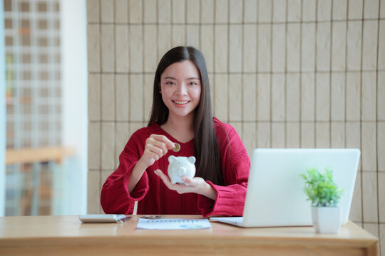 Young woman planning personal finances at home with a piggy bank, calculator, and coins, symbolizing saving, budgeting, investment, income, and future financial security.