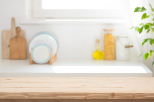 Empty wooden table top with blurred bright kitchen background for product placement