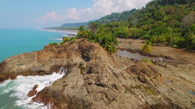 Jagged rocks meet crashing turquoise waves at pristine Perfecto Beach Costa Rica