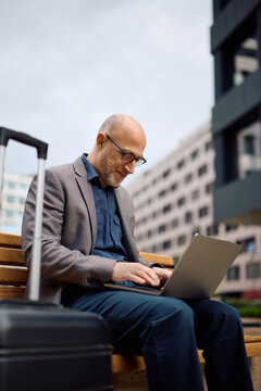Smiling businessman using on laptop while being on work trip.