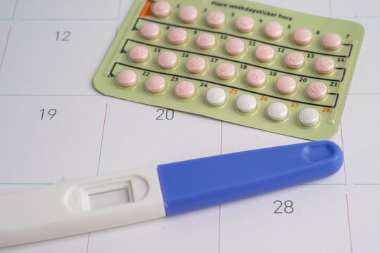 Pregnancy test and condom for female on calendar, ovulation day.