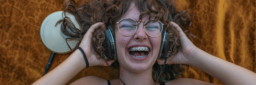 Laughing teenage girl listens to music on a portable CD player