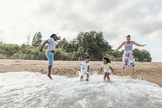 Happy family jumps in the water at the beach