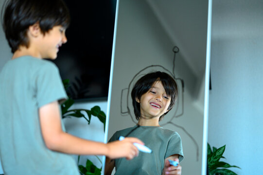 Boy draws an astronaut helmet on a mirror
