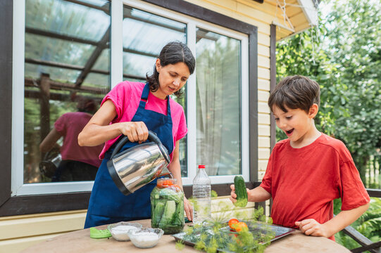 A mother and son prepare pickled vegetables together outdoors