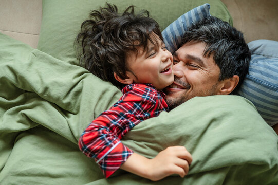 Happy father and son hug in bed during the morning at home
