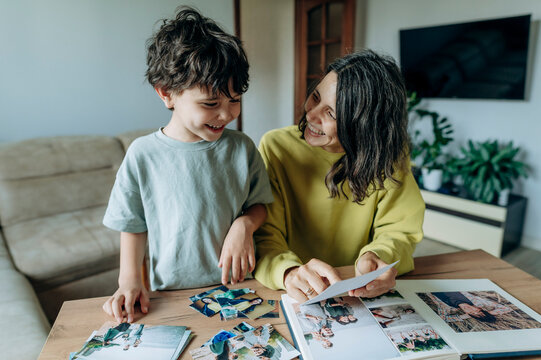 A mother and son look at a photo album together at home