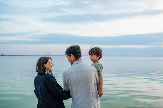 Happy family with son standing by the sea during summer vacation