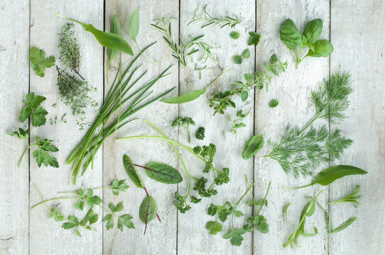 Different fresh herbs on white wood