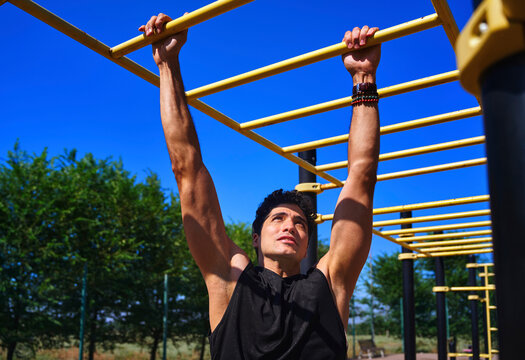A man grips a monkey bar during an outdoor workout