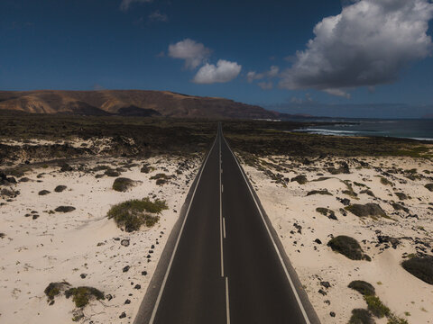 A straight road crosses the volcanic desert landscape in Lanzarote