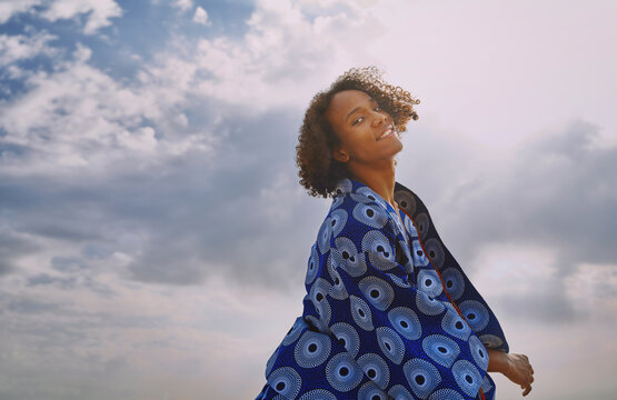 Smiling man in patchwork robe looking at camera against sky
