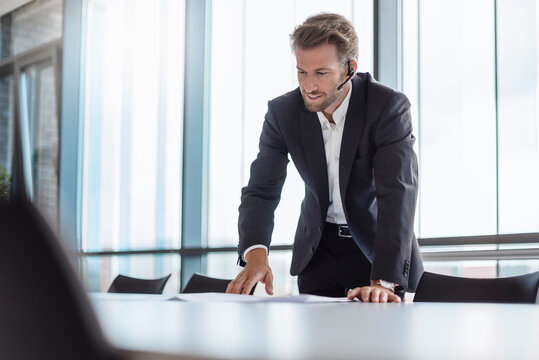 Businessman with bluetooth headset standing in conference room explaning