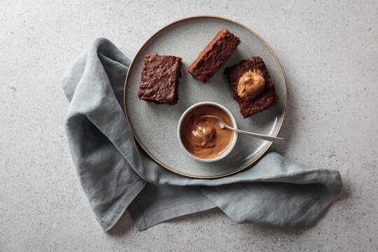 Vegan bean protein brownie rests on a plate with nut butter