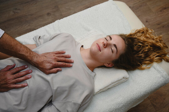 Doctor treats woman with manual therapy indoors