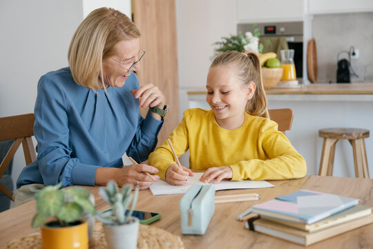 Grandmother and child doing homework together at home in kitchen