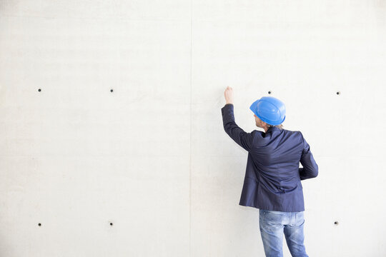 Man with hard hat on construction site drawing on concrete wall