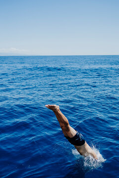 A diving man breaks the sea surface during summer vacation