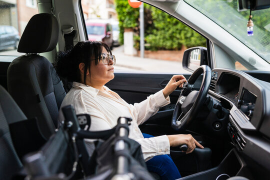 Woman driving an adapted car with hand control in urban setting