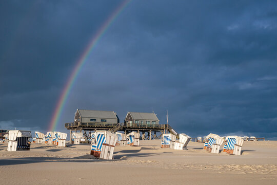 Rainbow over beach baskets and stilt houses in St. Peter-Ording