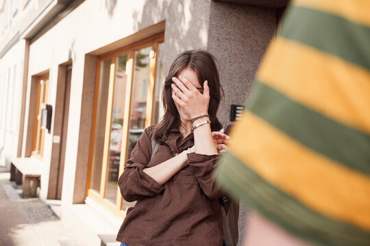 Woman covers her face in embarrassment while talking to a man