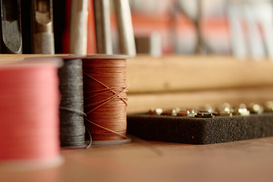 A spool of thread sits on a wooden table inside a craft workshop