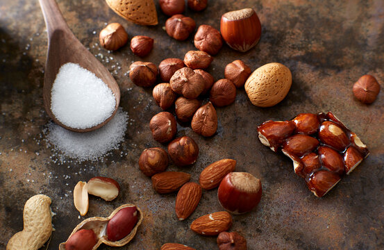 Homemade almond brittle, nuts and wooden spoon of sugar