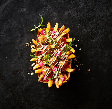 Loaded fast food with falafel and arugula on black background