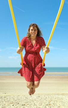 Woman in red dress swinging at the beach in Zoutelande Netherlands