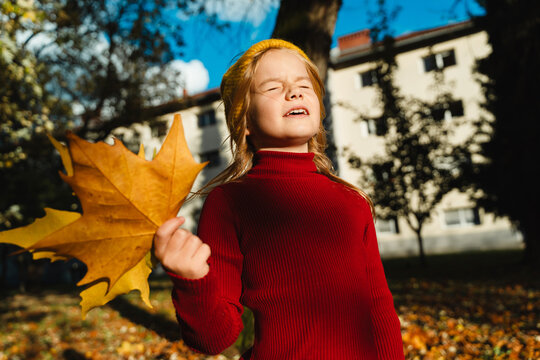 Girl in red sweater enjoys autumn sunshine outdoors