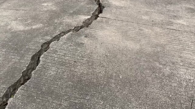 Large deep crack on gray concrete road pavement texture