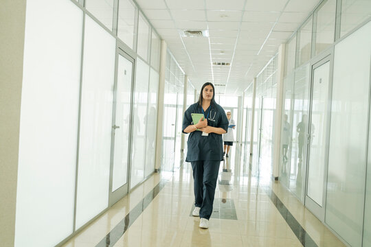 Female doctor walking with a tablet in a modern hospital corridor