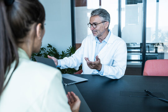 Male doctor gives advice to female patient at the office