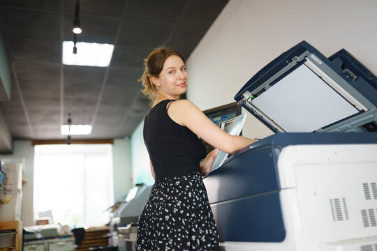 Female press operator uses a large printer in an office