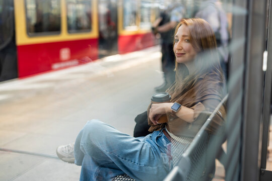 A woman in the city enjoys coffee while waiting for a train in Berlin
