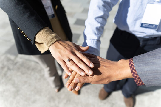 A business team stacks their hands together outdoors