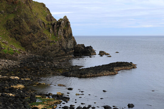 Landscape photo with a view of green hills, rocks and cliffs along the rocky coast Causeway Coastal Route near Kinbane Headland in Northern Ireland