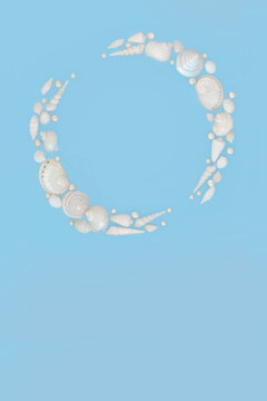 Shell wreath white and mother of pearl shells with pearls on blue background. Minimal abstract decoration frame design with iridescence colors,