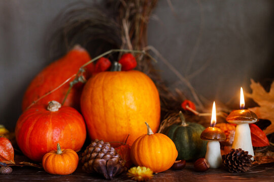 Happy Thanksgiving. Pumpkins, autumn leaves, nuts, mushroom candle on old wooden table on moody background. Atmospheric autumn still life with copy space. Fall season banner or card