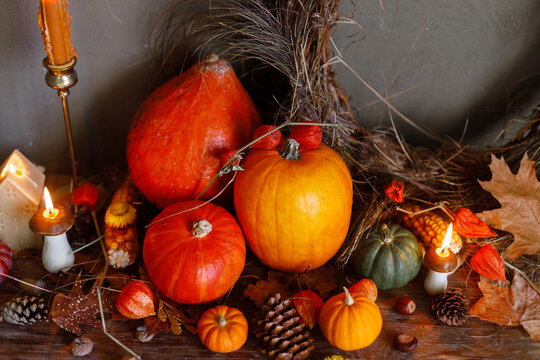 Happy Thanksgiving. Pumpkins, autumn leaves, nuts, rustic wreath, candle on old wooden table on moody background. Atmospheric autumn still life. Fall season banner or card