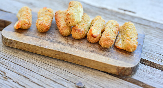 Vegetarian italian cheese breaded  oven baked  mozzarella sticks with  fresh basil on wooden background.Italian street food.