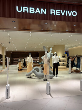 A modern retail store exterior with a prominent sign reading 'URBAN REVIVO'. Mannequins display various clothing styles. The layout features contemporary design elements and bright lighting.