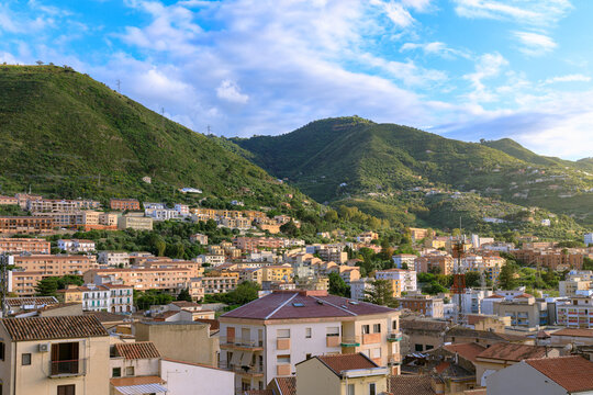 Picturesque coastal town nestled against lush green mountains under a bright summer sky