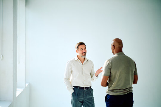 Two diverse men engaging in a focused business discussion, exchanging ideas and collaborating on a project in a bright office space