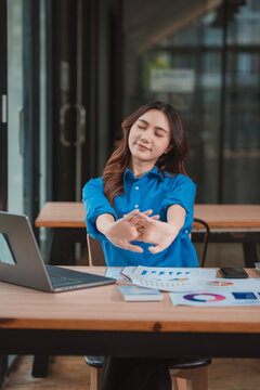 Asian businesswoman stretching arms and relaxing after finishing work at office desk