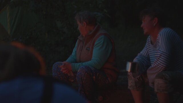 People sit in front of the bonfire burning in the wild area