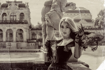 Obraz premium Beautiful blonde woman in gothic dress posing in vintage sepia photo style with scratched texture near classic baroque architecture 