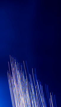 Abstract light trails streaking upward on dark blue background